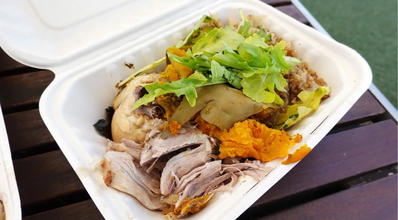 Takeaway box of hāngī — pulled pork, mashed kūmara, stuffing and fresh greens