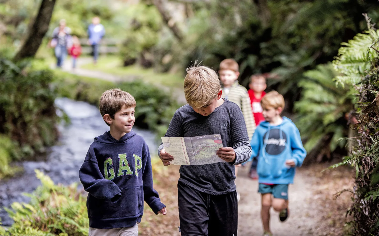 Children following the Buried Village trail with a guide map, beside the stream