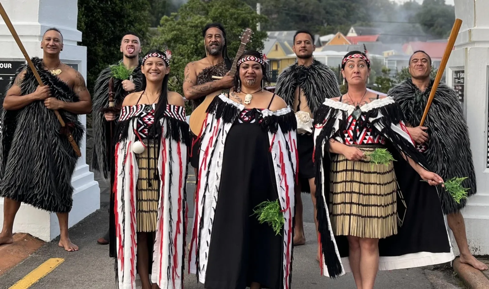 The Whakarewarewa performers gathered under the memorial arch, one holding a guitar