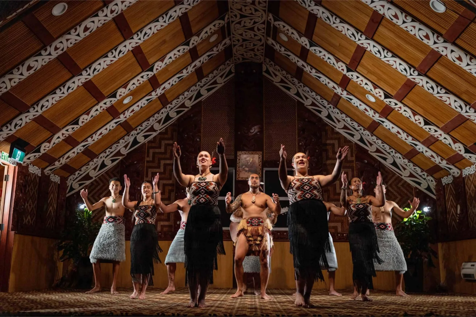 Te Puia performers singing inside the carved meeting house, beneath painted kōwhaiwhai rafters and tukutuku panels